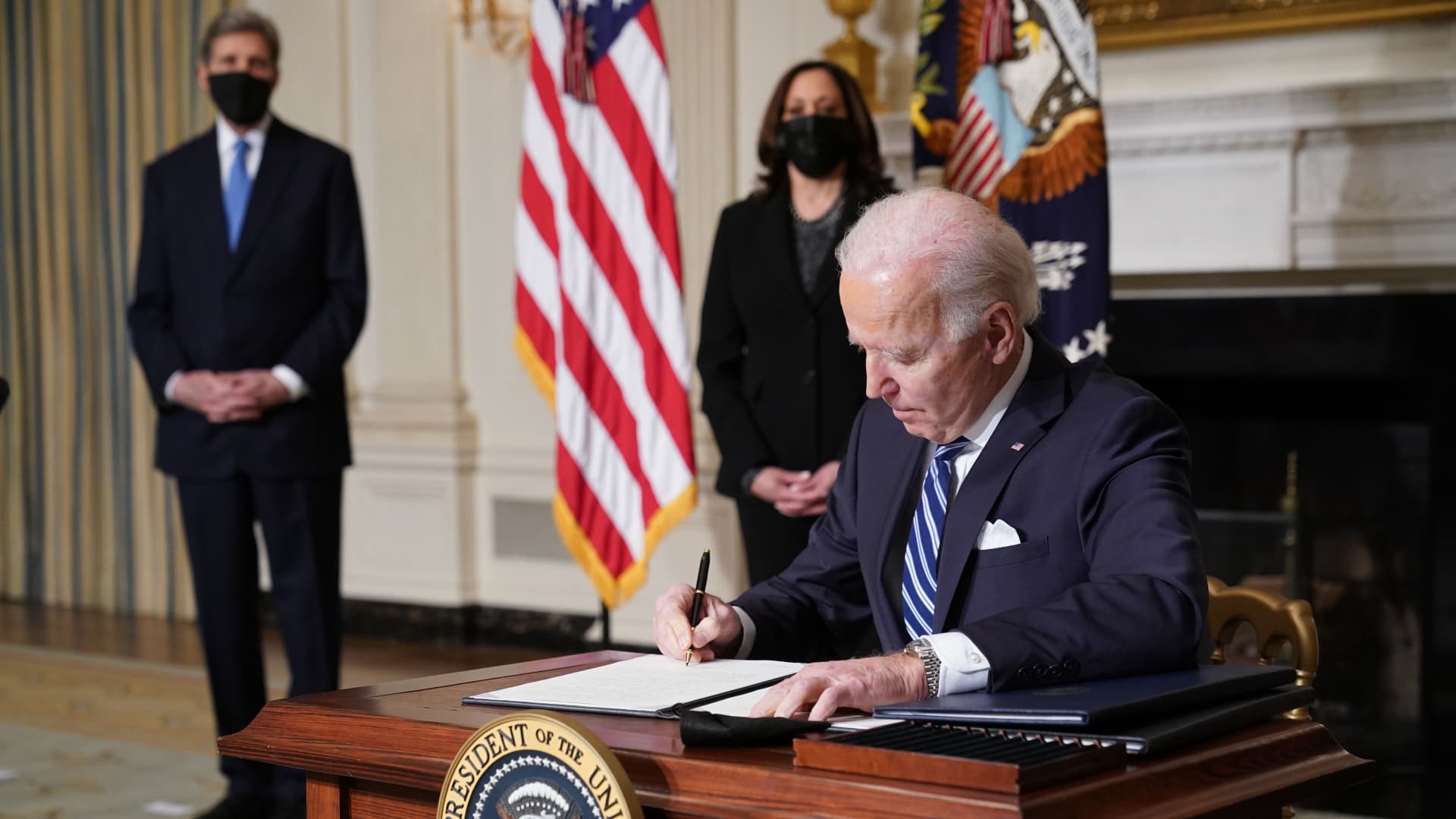 Vice President Kamala Harris (2-L) and Special Presidential Envoy for Climate John Kerry (L) watch as US President Joe Biden signs executive orders after speaking on tackling climate change, creating jobs, and restoring scientific integrity in the State Dining Room of the White House in Washington, DC on January 27, 2021.