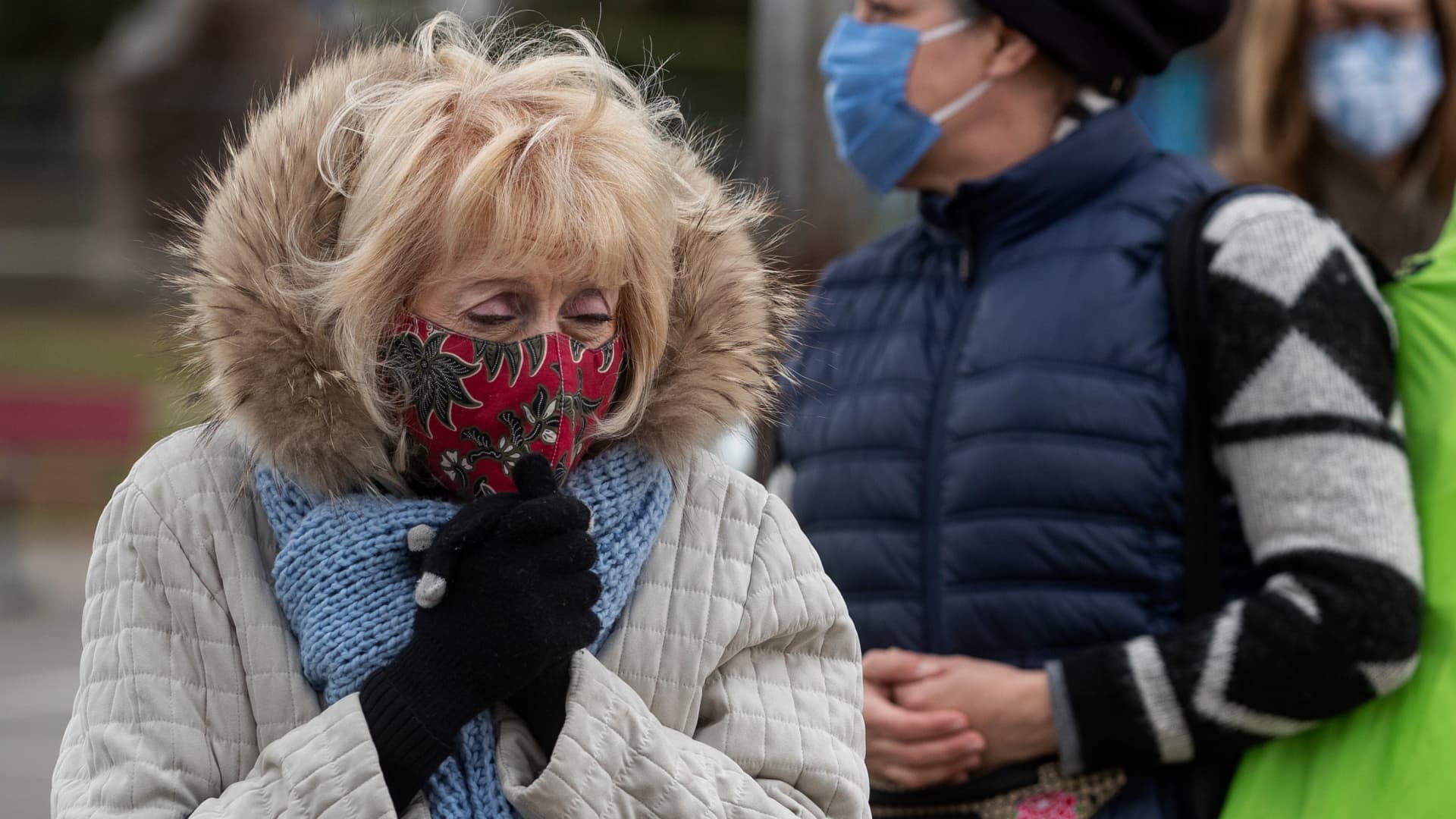 Evelyn Mellman, 82, of Studio City, tries to keep warm while waiting with others in the by appointment only line to get vaccine shots to protect against the coronavirus at the Balboa Sports Complex in Encino.