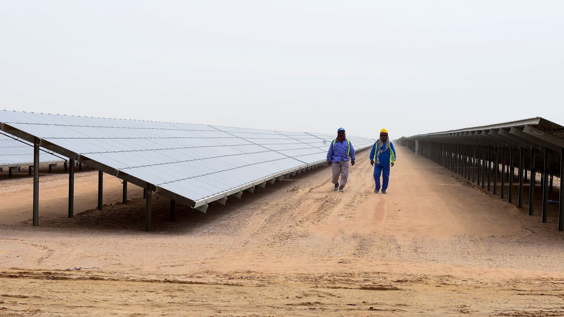 Workers photographed walking past a section of solar panels at the Mohammed bin Rashid Al-Maktoum Solar Park in Dubai on March 20, 2017.