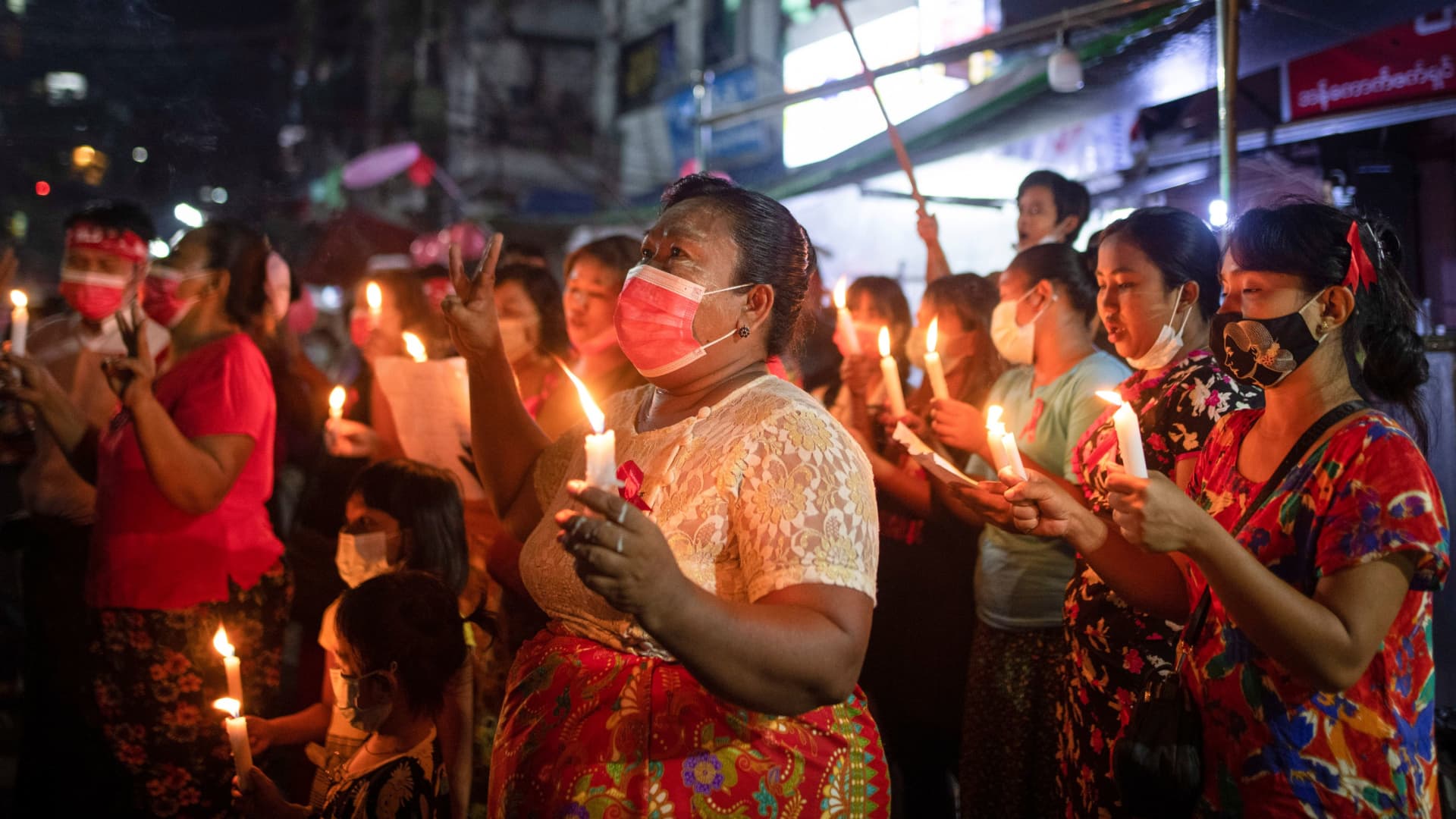 Women wearing red ribbons hold candles during a night protest against the military coup in Yangon, Myanmar February 5, 2021.