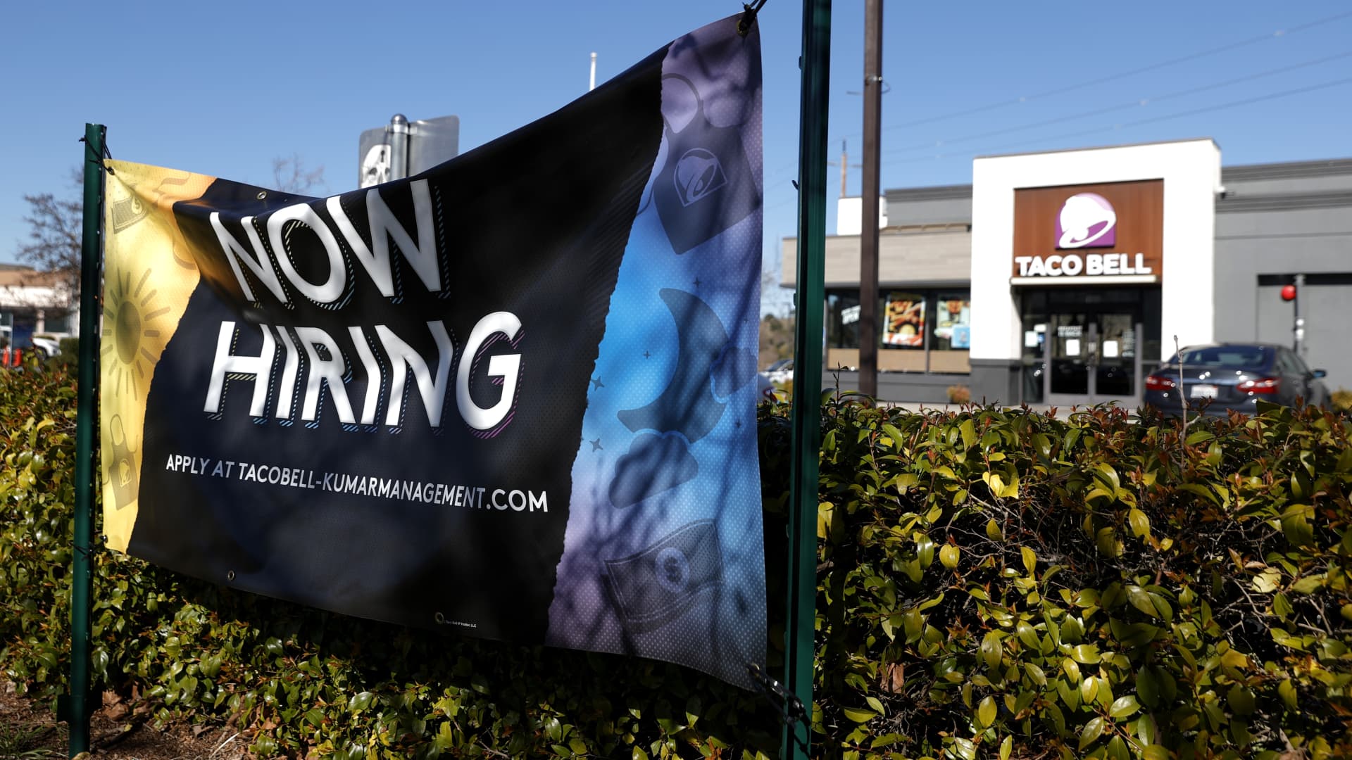 A Now Hiring sign is posted in front of a Taco Bell restaurant on February 05, 2021 in Novato, California.