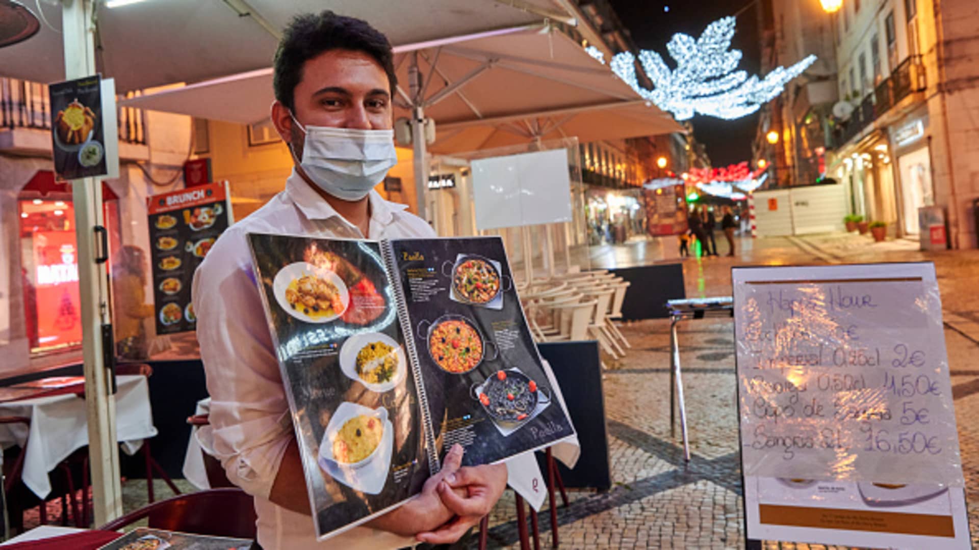 LISBON, PORTUGAL - A waiter wearing a protective mask shows the menu at one of the restaurants in Rua Augusta during the COVID-19 Coronavirus pandemic on November 23, 2020 in Lisbon, Portugal.