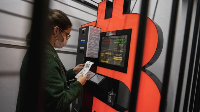 A woman uses a Bitcoin ATM machine placed within a safety cage on January 29, 2021 in Barcelona, Spain.