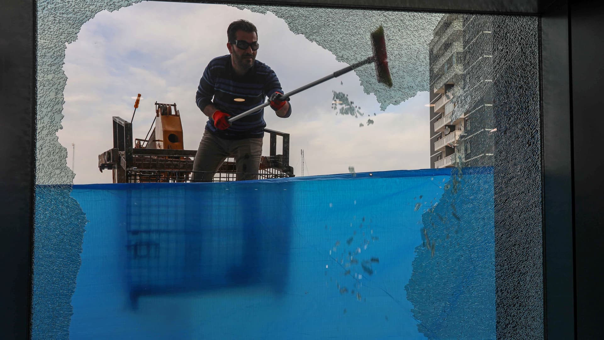A worker cleans shattered glass on February 16, 2021 outside a damaged shop following a rocket attack the previous night in Arbil, the capital of the northern Iraqi Kurdish autonomous region.