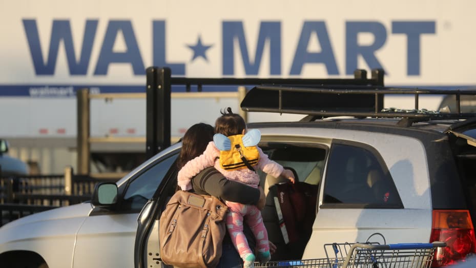 A shopper carrying a child returns to their car outside a Walmart store in Duarte, California, U.S., on Thursday, Nov. 12, 2020.