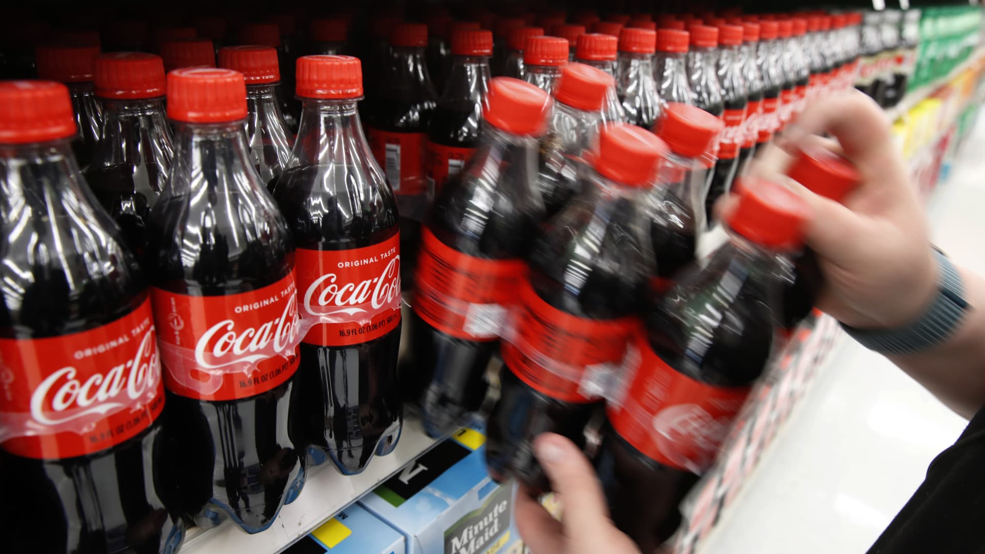 A worker restocks a display of Coca-Cola Co. soft drinks at a store in Orem, Utah, U.S., on Tuesday, Feb. 9, 2021.
