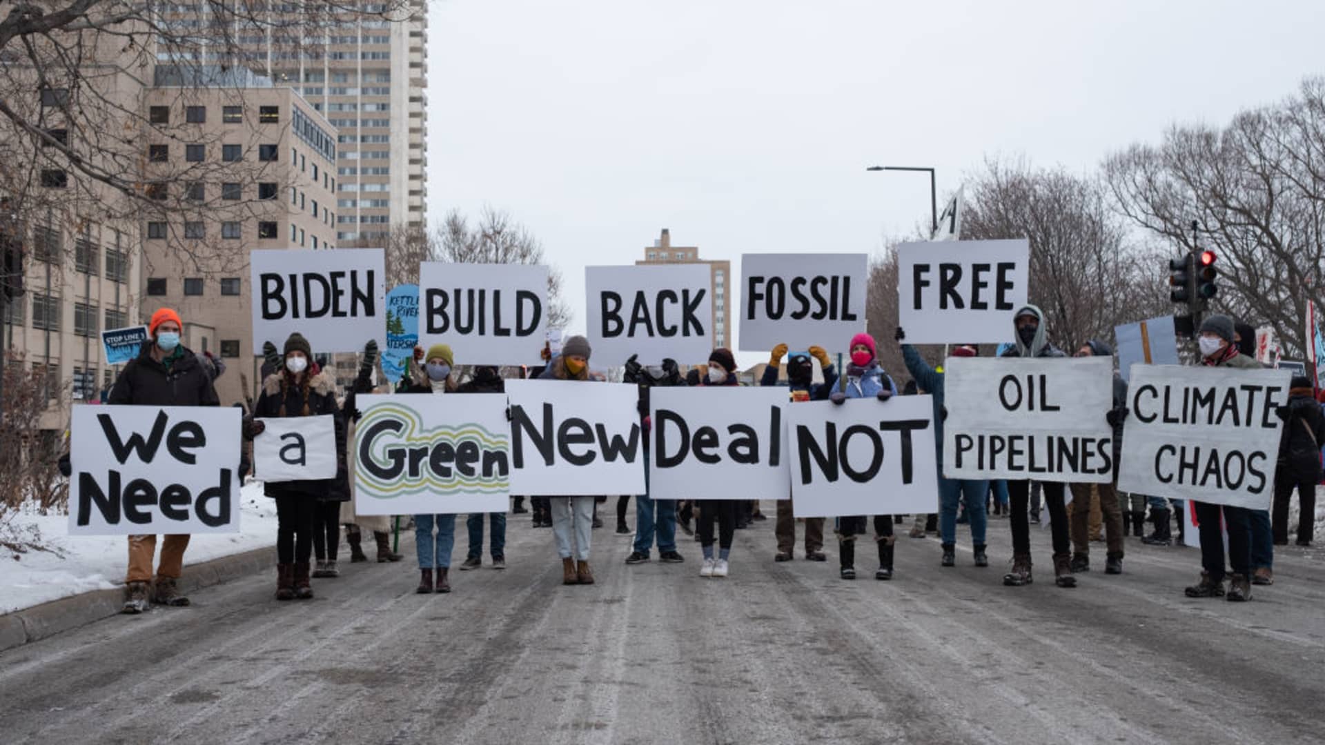 People hold signs calling for President Joe Biden to support a Green New Deal and end his support of pipelines and the fossil fuel industry.