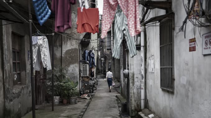 Una imagen que muestra ropa colgada de las líneas de la ropa sucia mientras una mujer pasa frente a edificios residenciales en Wuhan, China.