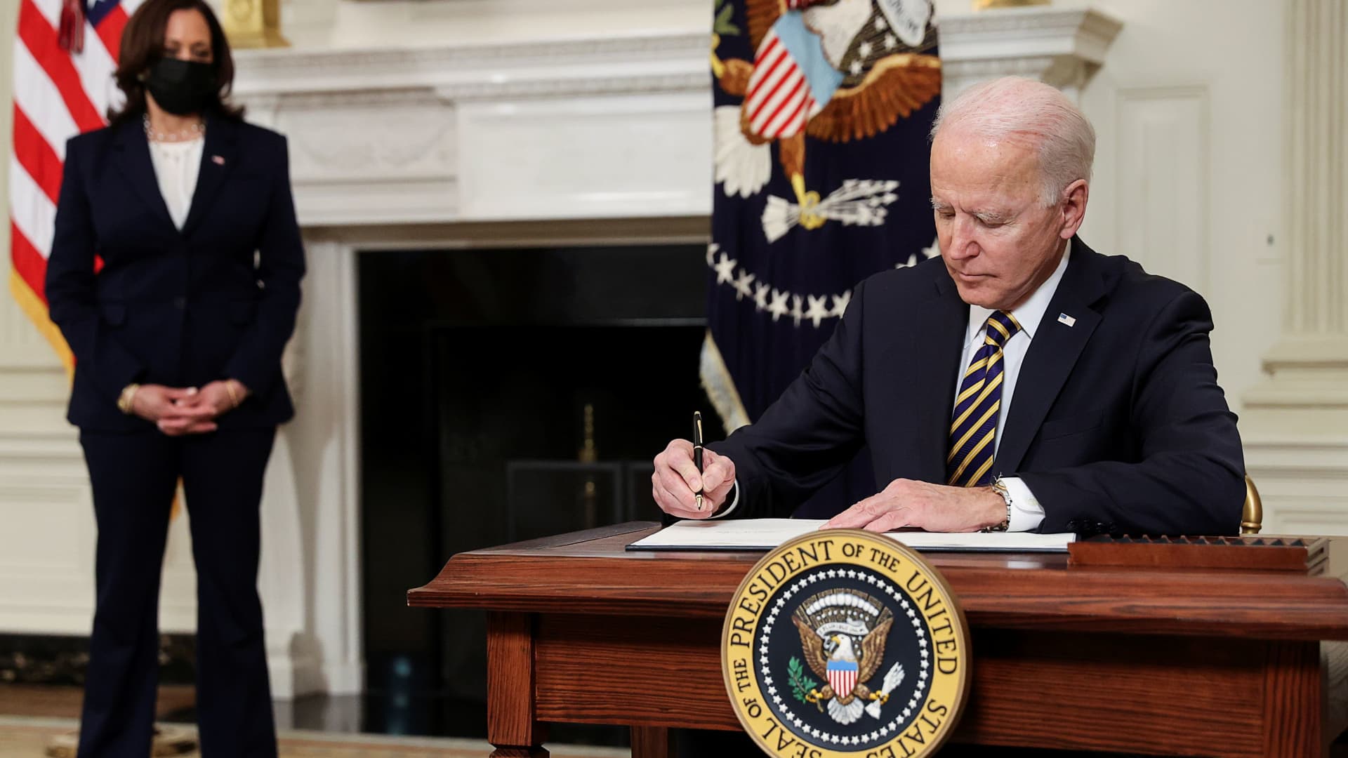 U.S. President Joe Biden signs an executive order, aimed at addressing a global semiconductor chip shortage, as Vice President Kamala Harris stands by in the State Dining Room at the White House in Washington, February 24, 2021.