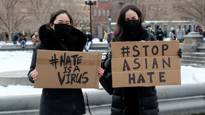 Protestors hold signs that read "hate is a virus" and "stop Asian hate" at the End The Violence Towards Asians rally in Washington Square Park on February 20, 2021 in New York City.