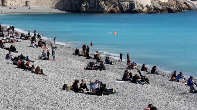 People sit on the "Castel" beach along the "Promenade des anglais" on the French Riviera city of Nice, southern France.