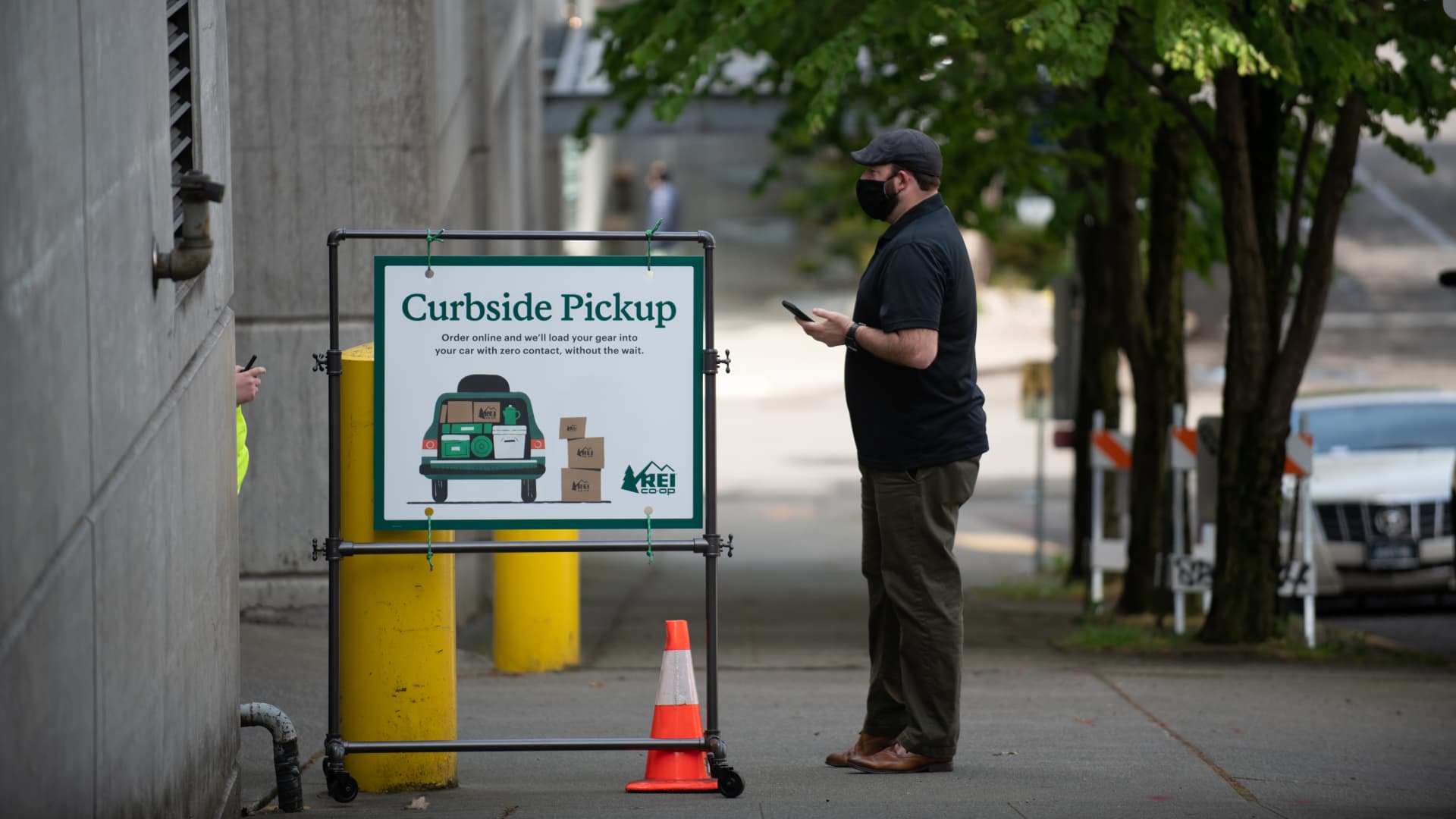 A customer waits for a contactless curbside pickup at the Recreational Equipment Inc. (REI) flagship store in Seattle, Washington, U.S., on Thursday, May 14, 2020.