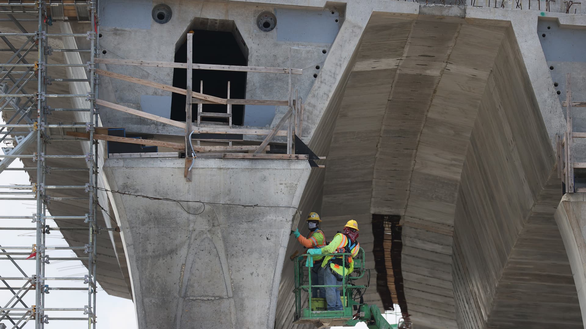Construction workers build the “Signature Bridge,” replacing and improving a busy highway intersection at I-95 and I-395 on March 17, 2021 in Miami, Florida.