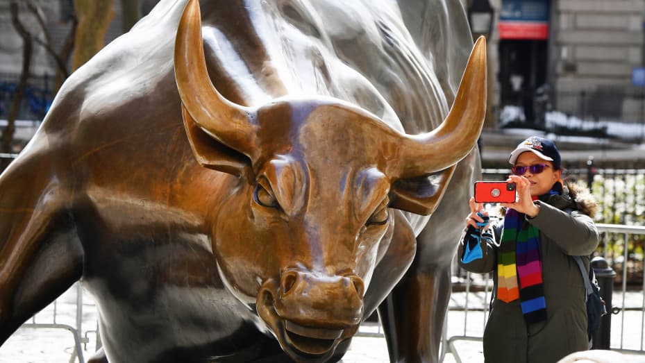 A woman takes a selfie with the 'Charging Bull' statue on February 17, 2021 in New York City.