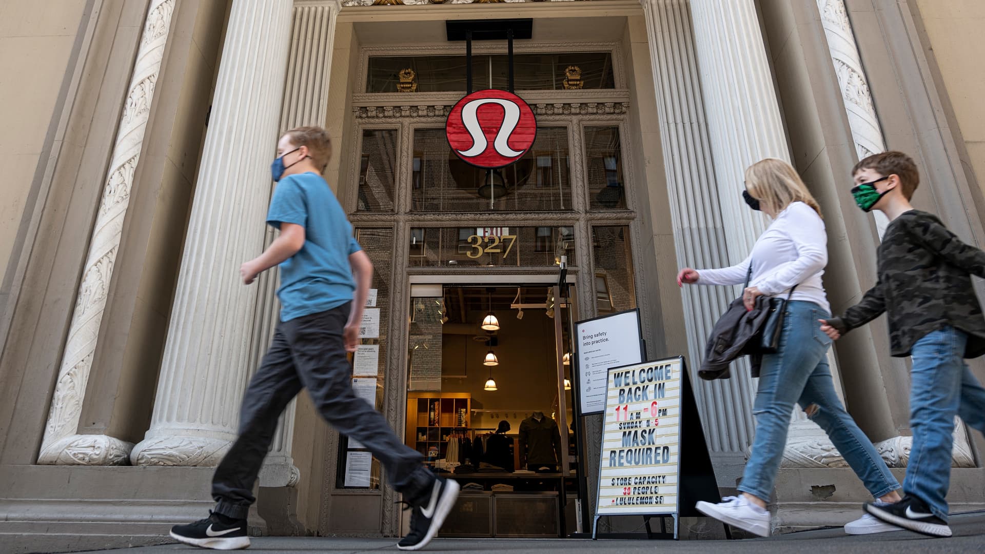 Pedestrians wearing protective masks walk past a Lululemon store in San Francisco, California, on Monday, March 29, 2021.