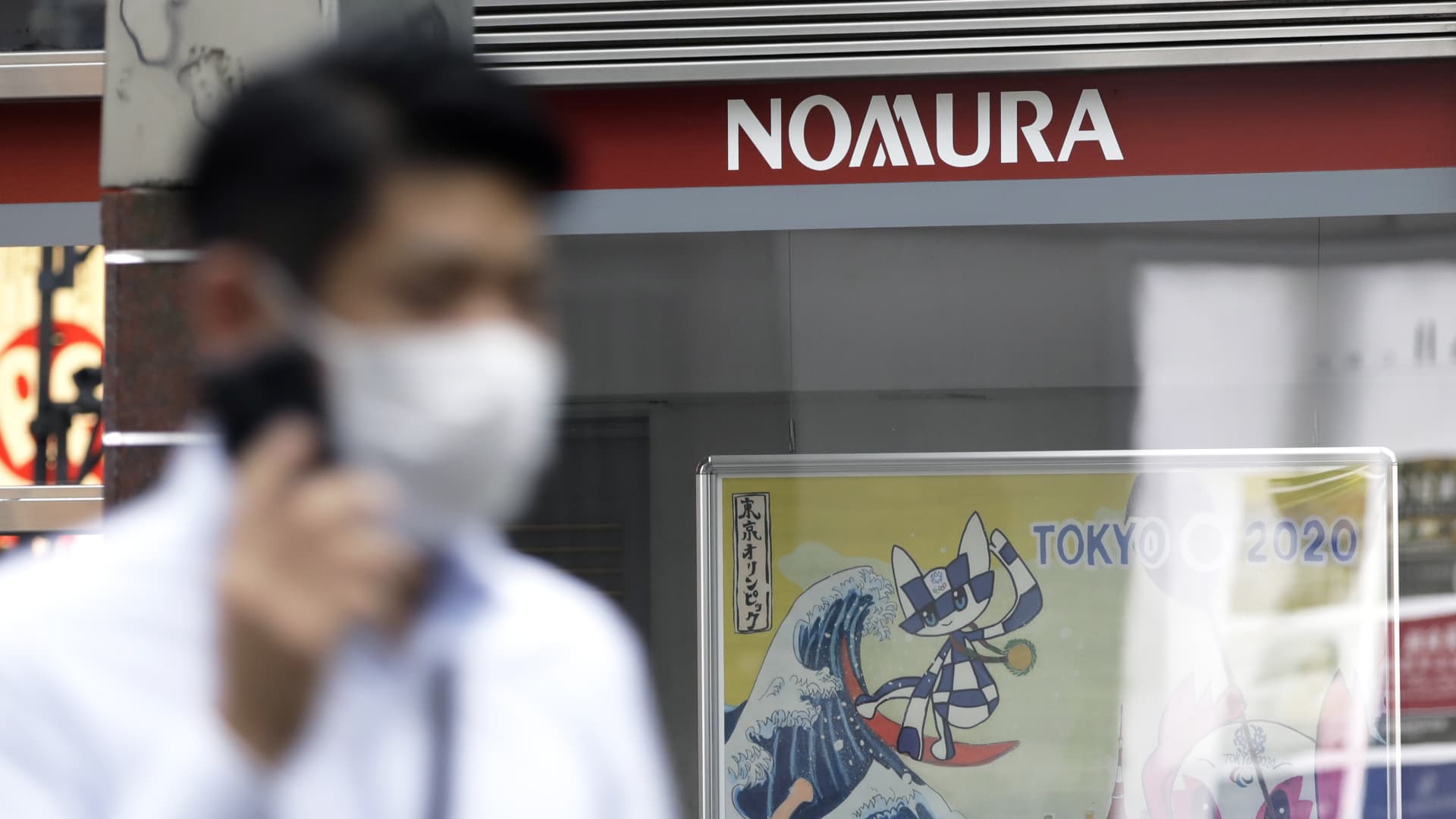 A pedestrian wearing a protective mask walks past a branch of Nomura Securities Co., a unit of Nomura Holdings Inc., in Tokyo, Japan, on Monday, July 27, 2020.