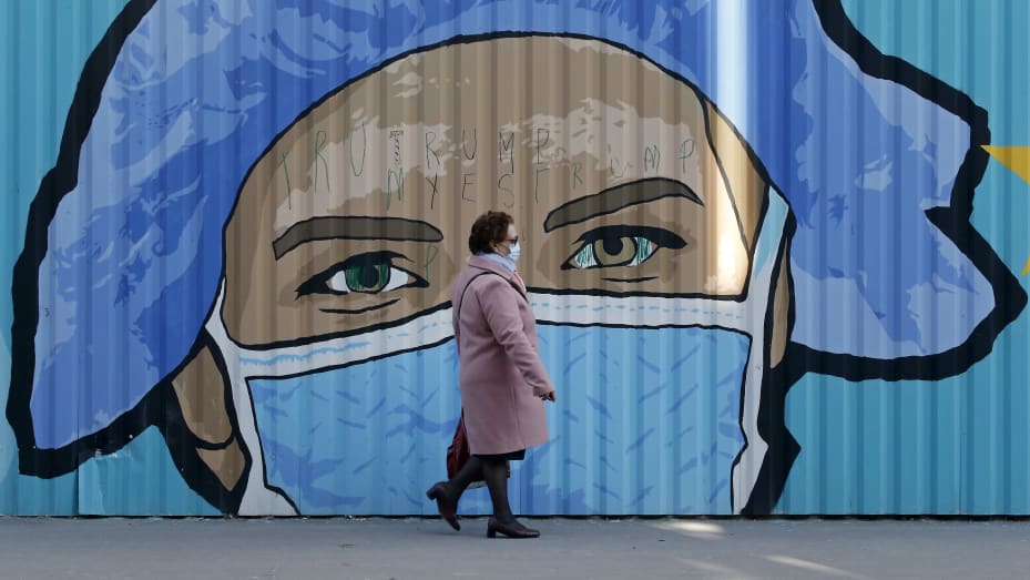 Un peatón con una mascarilla protectora pasa junto a un mural de arte callejero del artista callejero francés JBC, en homenaje a los trabajadores de la salud que representan a una enfermera con una mascarilla protectora en referencia a la enfermedad por coronavirus (COVID-19) el 24 de marzo de 2021 en París. ,