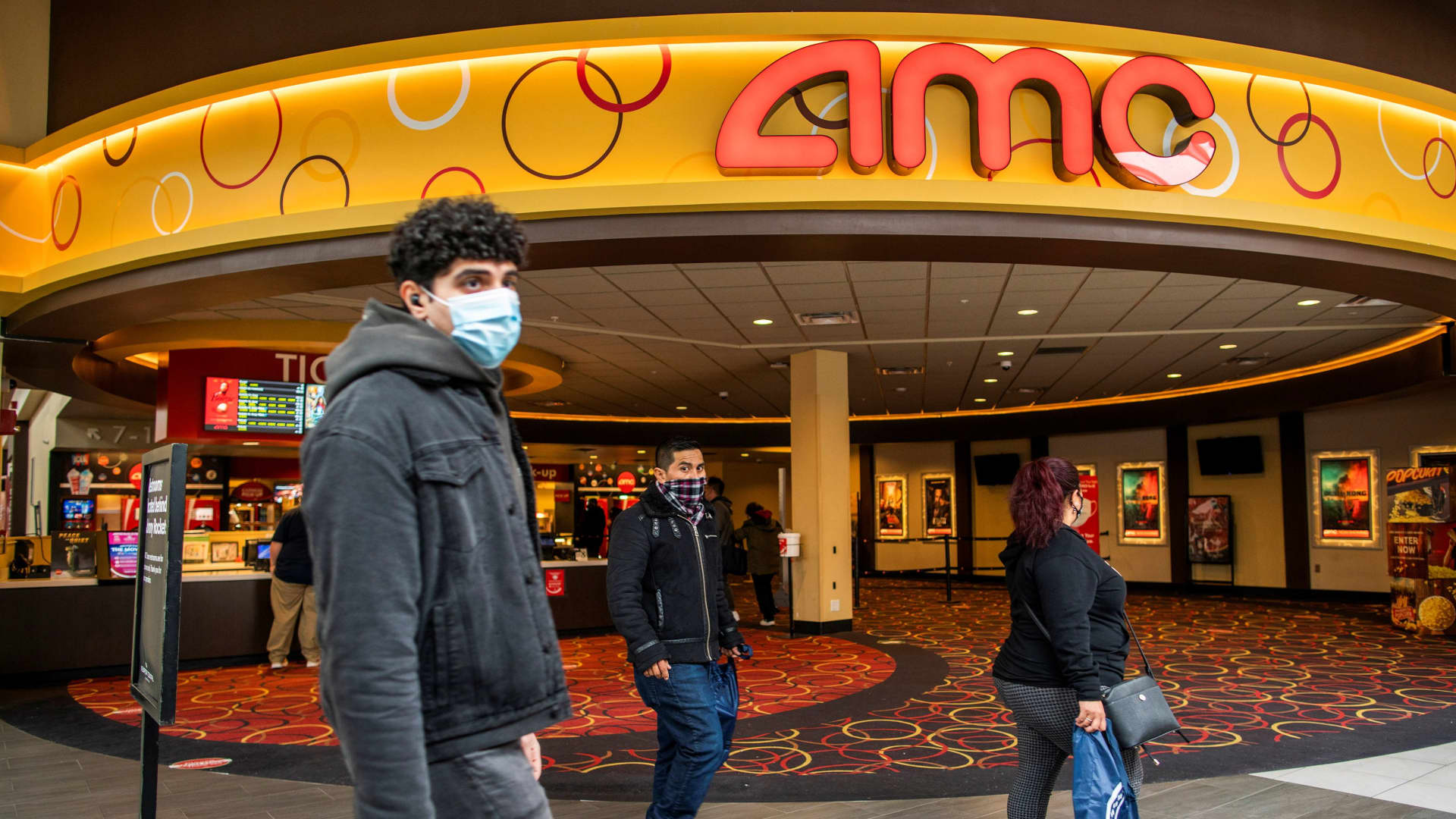 People wear face masks as they walk by a movie theater during the coronavirus disease (COVID-19) pandemic in Newport, New Jersey, April 2, 2021.