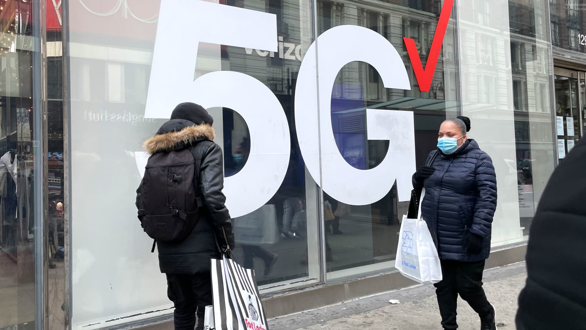 Pedestrians walk by a Verizon 5G sign in New York, April 3, 2021.