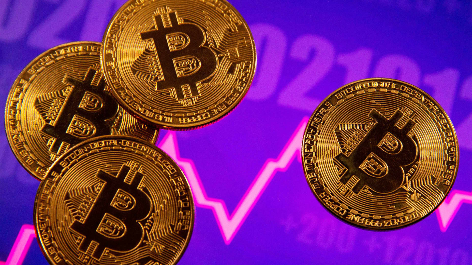 A representation of virtual currency Bitcoin is seen in front of a stock graph in this illustration.