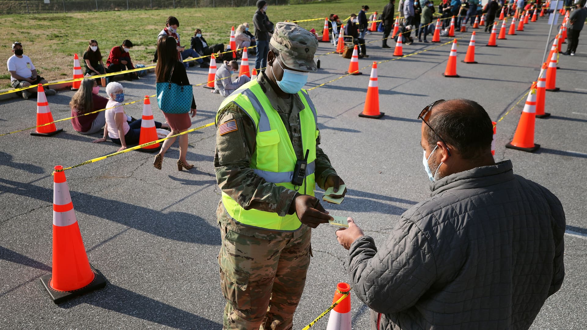 A member of the Maryland National Guard hands out Post-It notes with numbers to people arriving without appointments at the mass coronavirus vaccination site at Hagerstown Premium Outlets on April 07, 2021 in Hagerstown, Maryland.