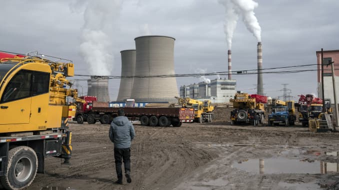 A person walks past a coal fired power plant in Jiayuguan, Gansu province, China, on Thursday, April 1, 2021.