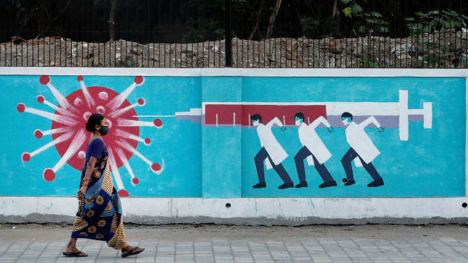 A woman wearing a protective face mask walks past a graffiti, amidst the spread of the coronavirus disease (COVID-19), on a street in Mumbai, India, March 30, 2021.