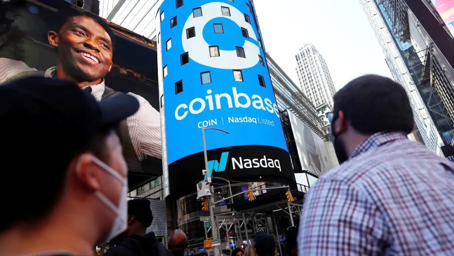 People watch as the logo for Coinbase Global Inc, the biggest U.S. cryptocurrency exchange, is displayed on the Nasdaq MarketSite jumbotron at Times Square in New York, U.S., April 14, 2021.