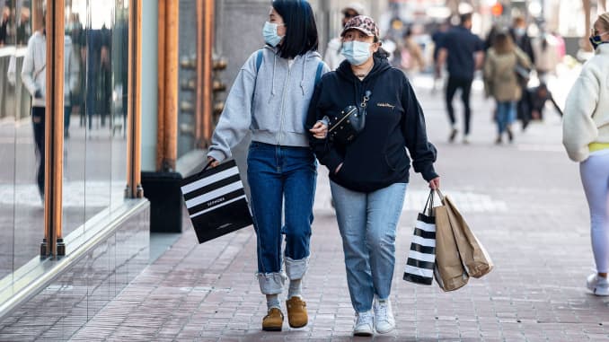 Los compradores que llevan máscaras protectoras llevan bolsas en Market Street en San Francisco, California, el miércoles 14 de abril de 2021.