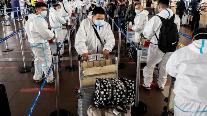 Passengers in protective suits against the spread of the novel coronavirus disease, queue at counters at Arturo Merino Benitez International Airport in Santiago on April 1, 2021, after Chile announced it will close its borders in April as of Monday amid a surge in COVID-19 cases.