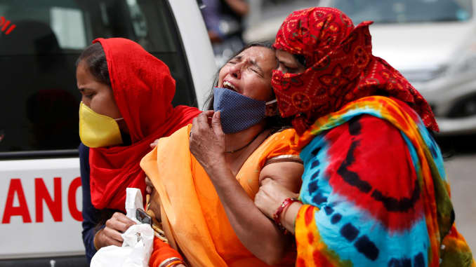 A woman is consoled after her husband died due to the coronavirus disease (COVID-19) outside a mortuary of a COVID-19 hospital in Ahmedabad, India, April 20, 2021.