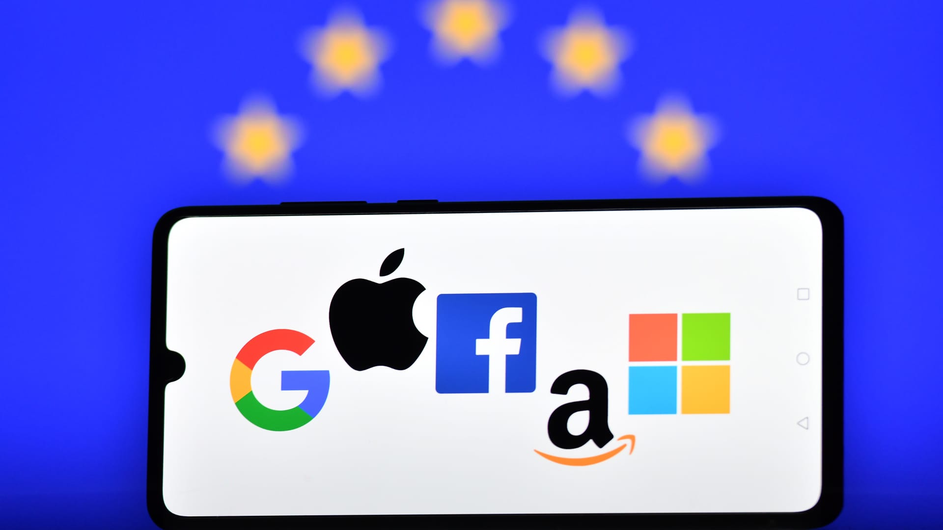 The logos of Google, Apple, Facebook, Amazon and Microsoft displayed on a mobile phone with an EU flag shown in the background.