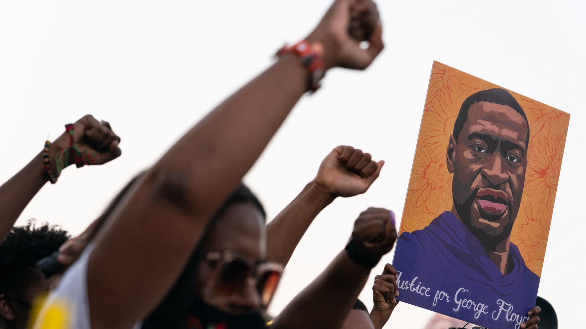 People raise their fists and hold a portrait of George Floyd during a rally following the guilty verdict the trial of Derek Chauvin on April 20, 2021, in Atlanta, Georgia.
