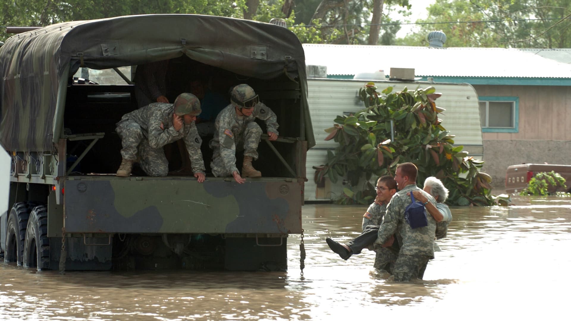 Texas National Guard Pvt. Mark Rivera of Co. A, 72nd Infantry Brigade, and Pvt. 1st Class Joseph Davora, Co. A, 1-41 Infantry Regiment, carry a woman stranded by flood waters to a waiting truck, where Pvt. John Paul Borrego and Pvt. 1st Class Christopher Culbelier, wait.