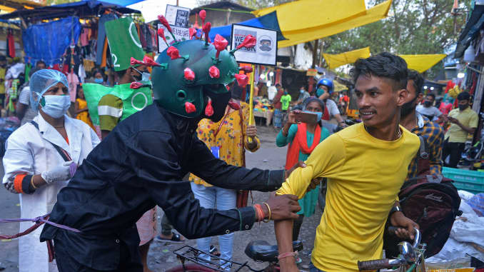 A man from a Non-governmental organization (NGO) wearing an outfit resembling the Covid-19 coronavirus moves around a marketplace urging people to follow the safety protocols during an awareness drive held in Siliguri on April 25, 2021.