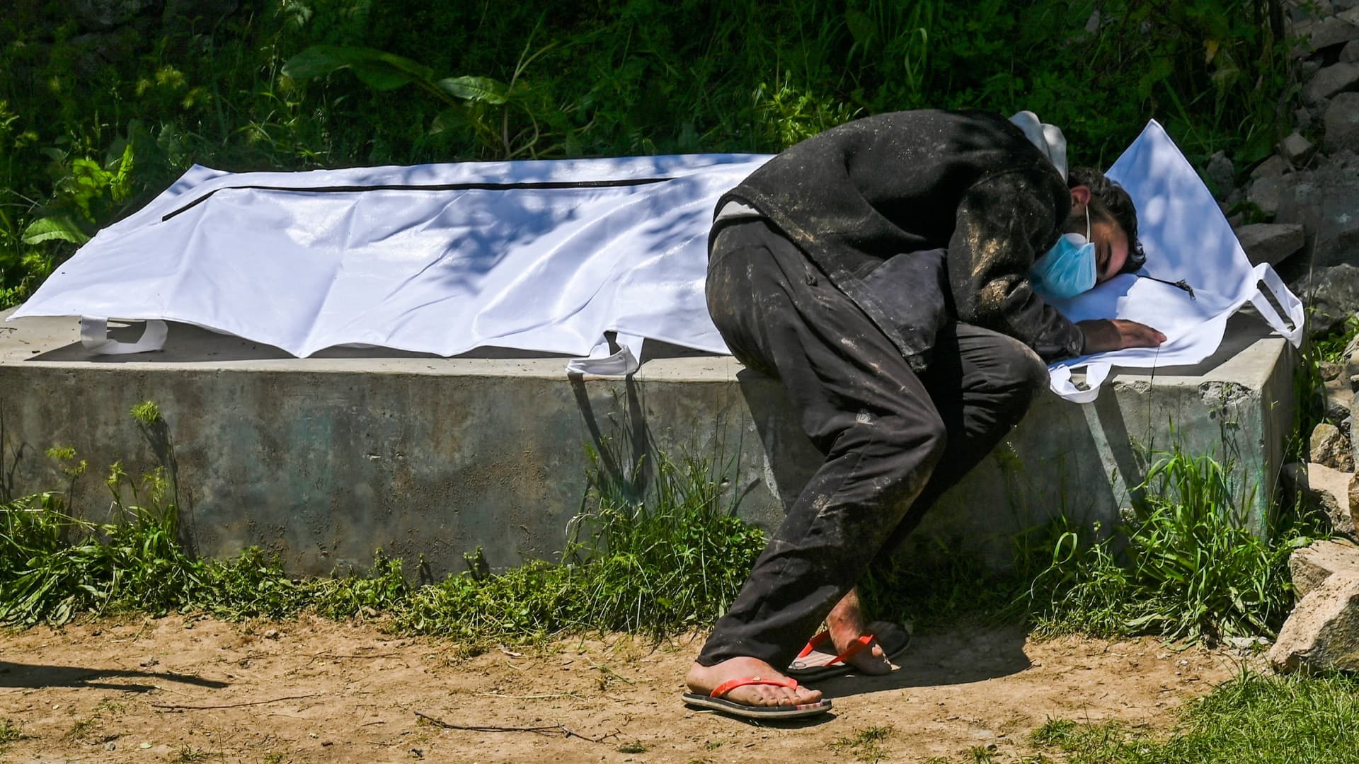 Umar Farooq mourns over to the body of his mother, who died of Covid-19 coronavirus, before her burial at a graveyard in Srinagar on April 26, 2021.
