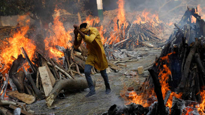 A man runs past the burning funeral pyres of those who died from the coronavirus disease (COVID-19), during a mass cremation, at a crematorium in New Delhi, India April 26, 2021.