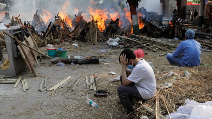Family members sit next to the burning funeral pyres of those who died from the coronavirus disease (COVID-19), during a mass cremation, at a crematorium in New Delhi, India April 26, 2021.