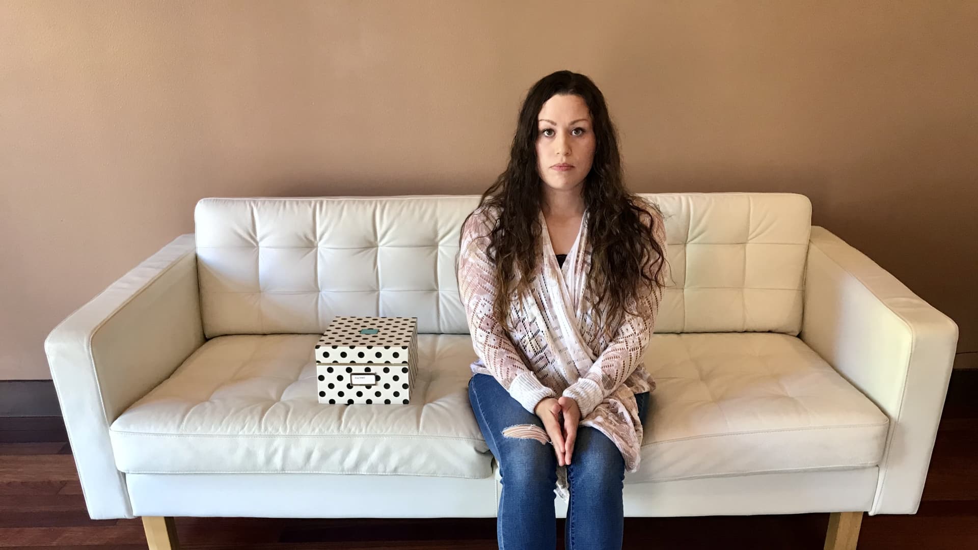 Annabel Adams, 37, sits with a polka dot box where she keeps all the ultrasound images of her five lost pregnancies.