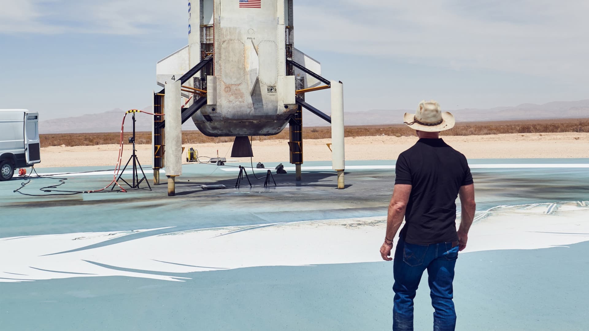 Jeff Bezos takes a look at the New Shepard rocket booster on the landing pad after a successful NS-15 flight and landing in April 2021.