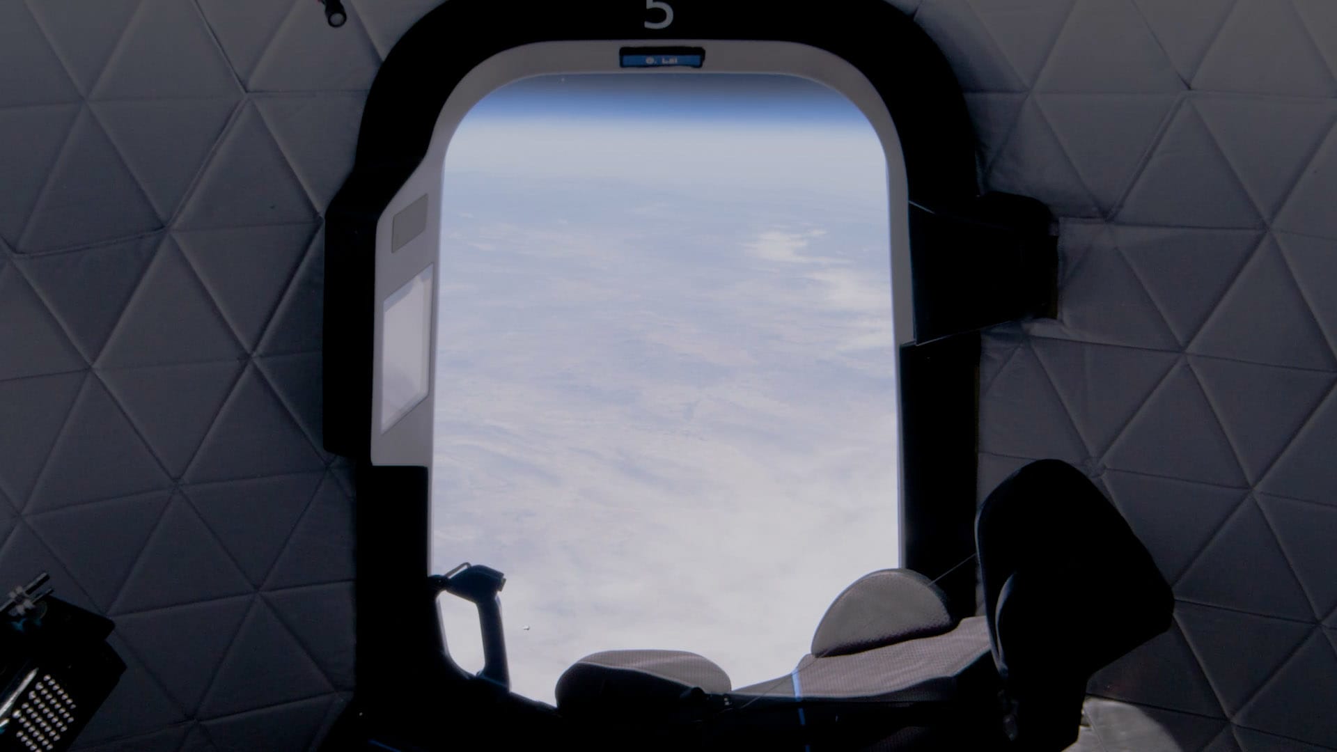 A seat and the view from inside a New Shepard capsule at the edge of space.