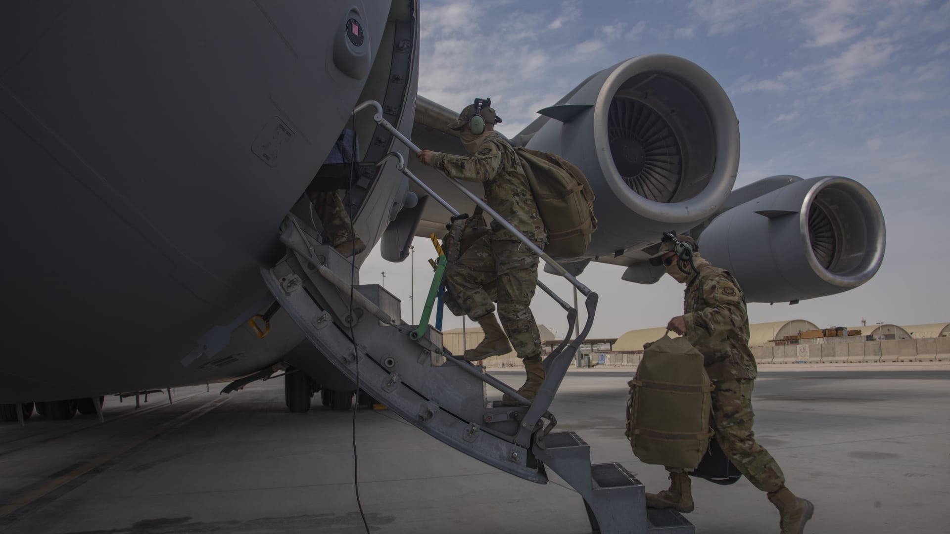 Aircrew assigned to Al Udeid Air Base, Qatar, carry their gear into a C-17 Globemaster III assigned to Joint Base Charleston, South Carolina, April 27, 2021.