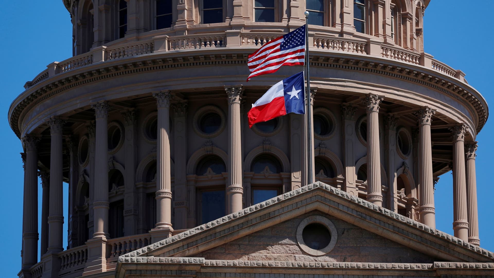The American flag and the Texas State flag fly over the Texas State Capitol in Austin, Texas.