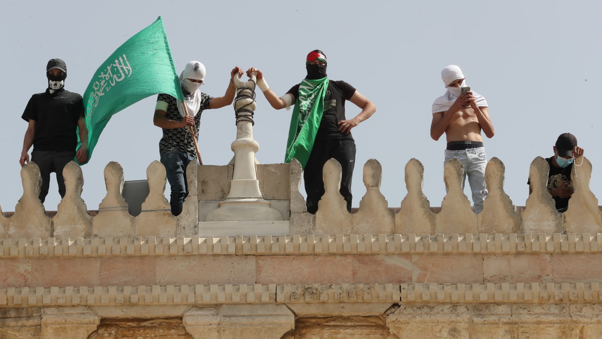 A Palestinian holds a Hamas flag atop a walk of Al-Aqsa mosque following clashes with Israeli police in Jerusalem's Old City May 10, 2021.