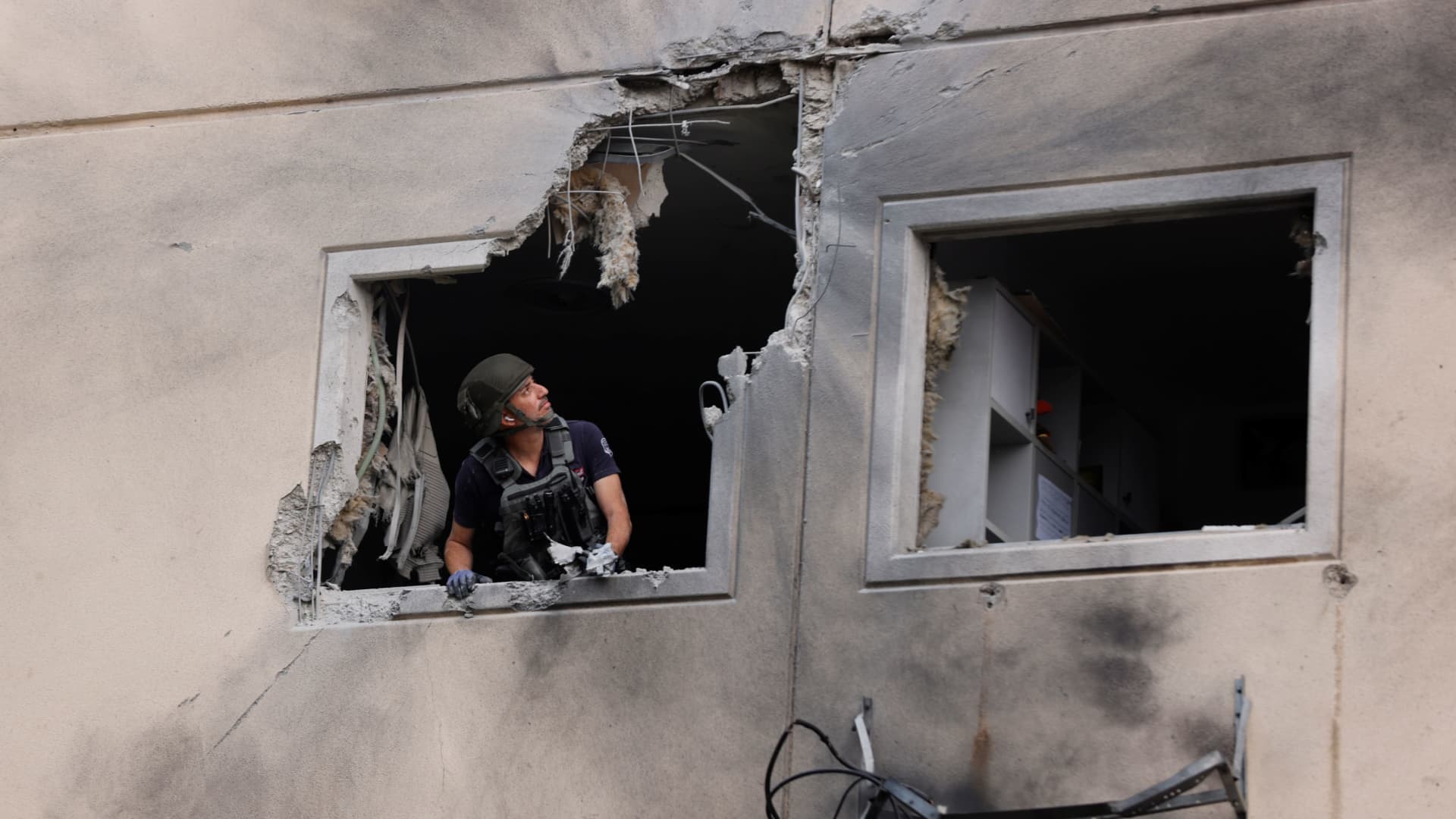 An Israeli police bomb disposal expert looks out from the window of a residential building that was damaged after it was hit by a rocket launched from the Gaza Strip, in Ashkelon, southern Israel May 11, 2021.