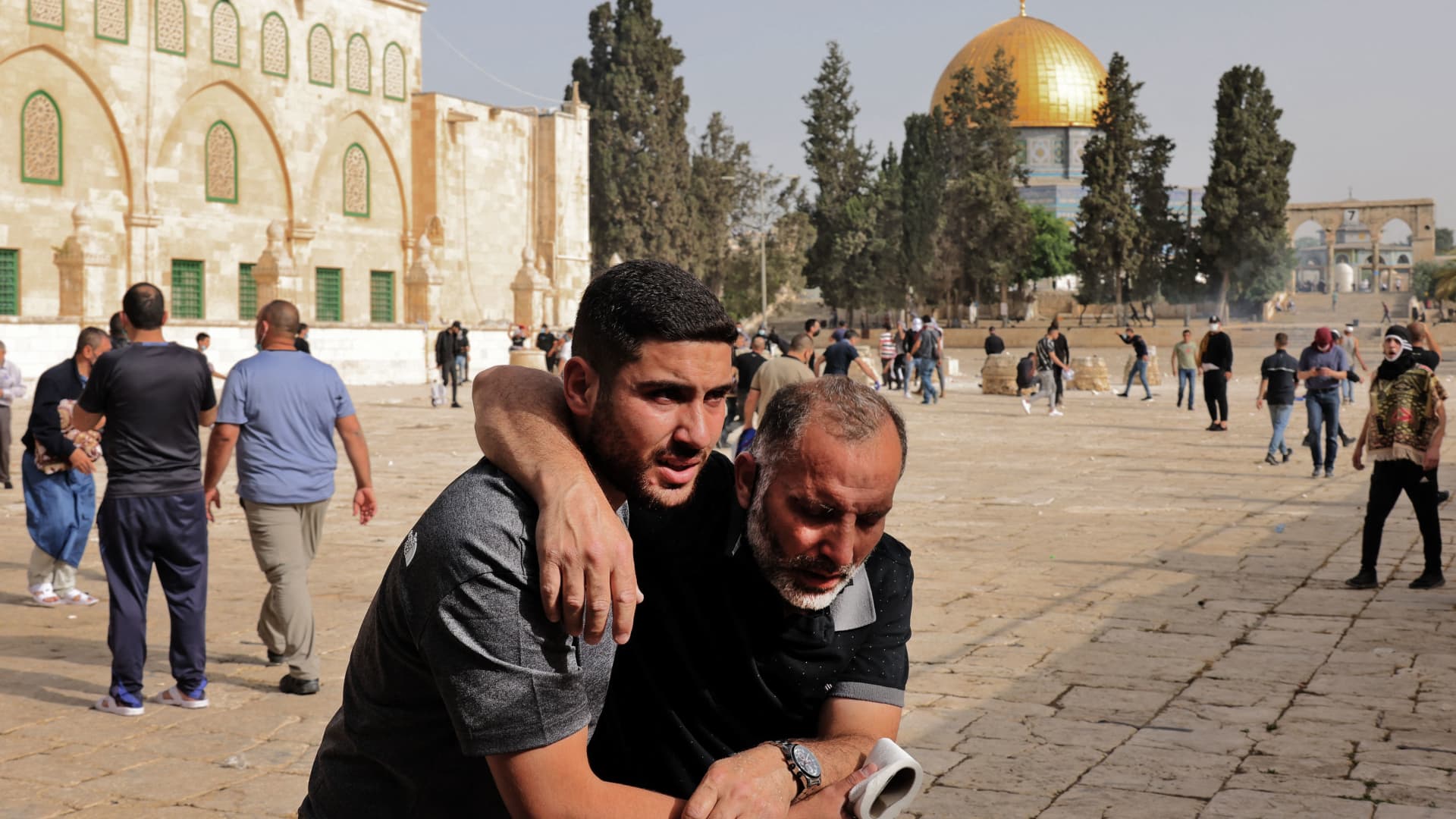A Palestinian man helps a wounded fellow protester amid clashes with Israeli security forces at Jerusalem's Al-Aqsa mosque compound on May 10, 2021, ahead of a planned march to commemorate Israel's takeover of Jerusalem in the 1967 Six-Day War.