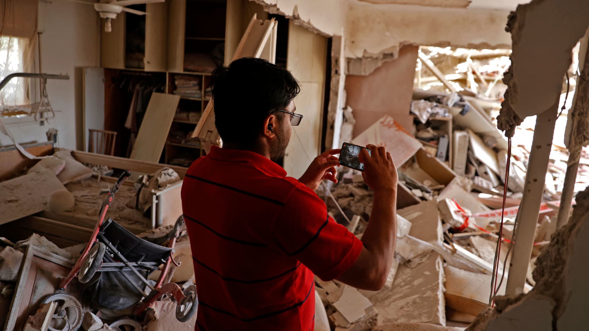 An Israeli man takes a picture of a heavily damaged house in the southern Israeli city of Ashkelon on May 11, 2021, as rockets are fired by the Hamas movement from the Gaza Strip toward Israel.