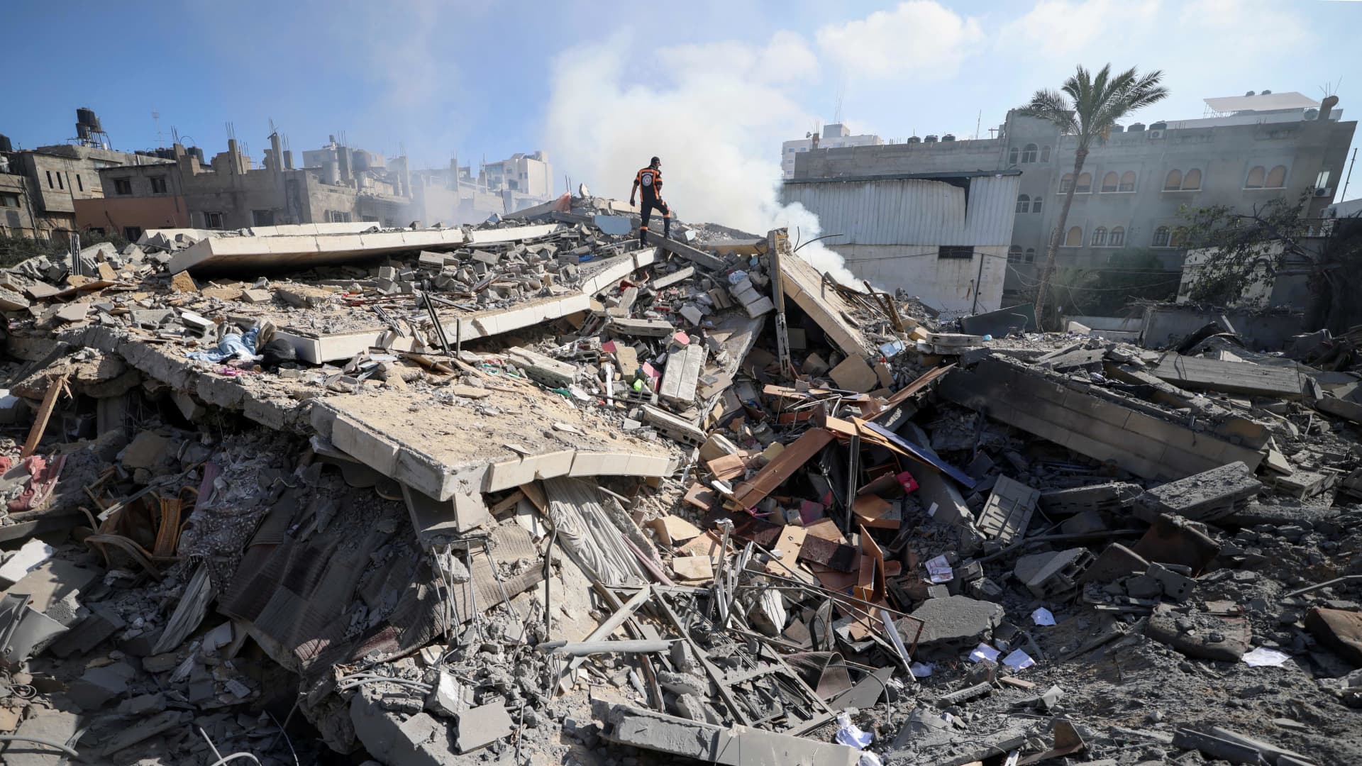 A member of the Palestinian civil defence walks amidst the rubble of a building in Gaza city which housed the Intaj Bank linked to the Hamas movement which controls the Gaza Strip, on May 15, 2021.