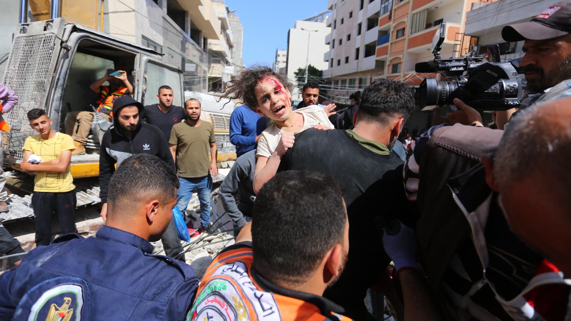 People rescue a wounded child from a debris as search and rescue works continue at a debris of a building after airstrikes by Israeli army hit buildings in al-Rimal neighborhood of Gaza City, Gaza on May 16, 2021.