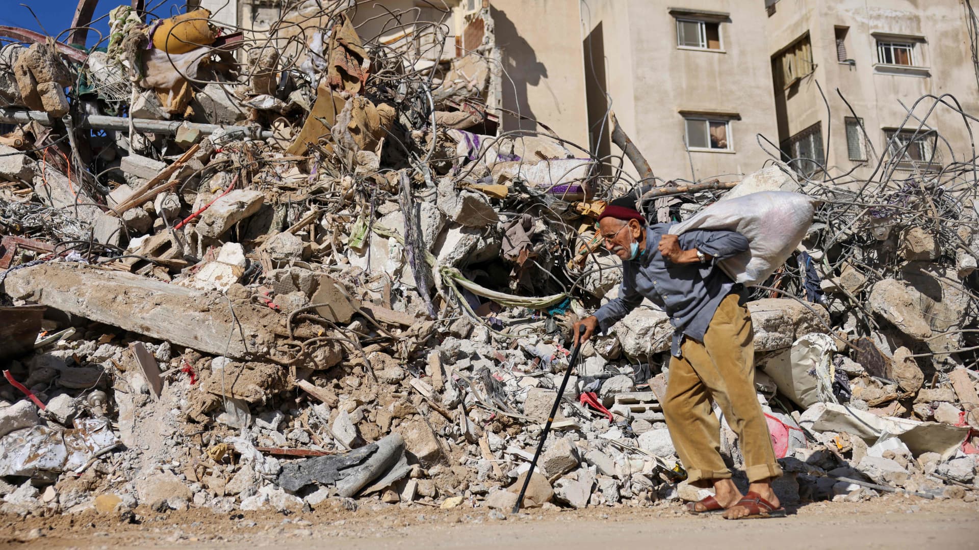 A Palestinian elderly man walks past a building destroyed by Israeli bombardment in Gaza City, on May 19, 2021.